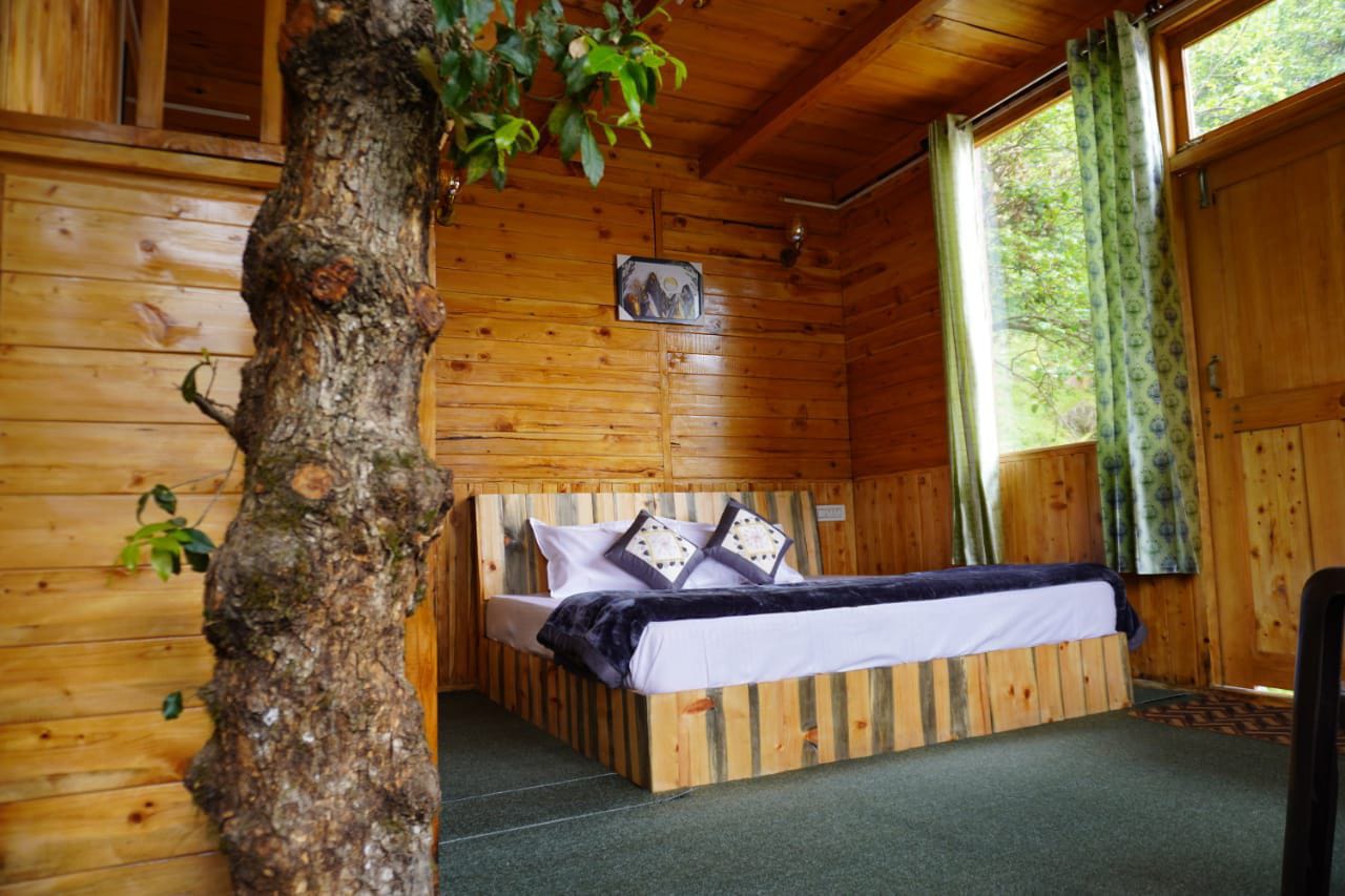 Bedroom with a tree growing through the room at Woodland Treehouse Jibhi